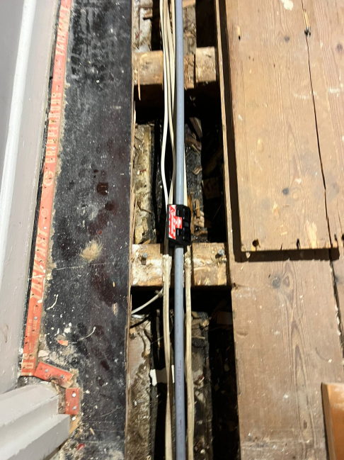 Pipes run beneath floorboards during a plumbing installation