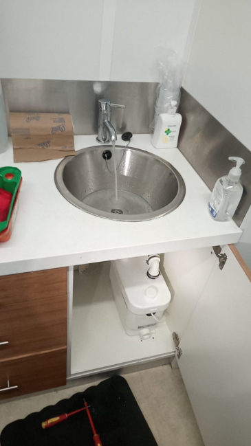 Round stainless steel sink with Saniflo pump unit installed underneath