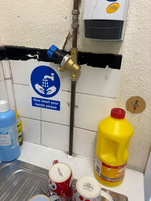 Commercial pipework with isolation valve and handwashing sign